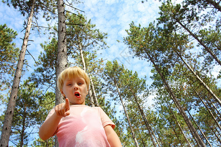 一个年幼的孩子站在森林外面图片