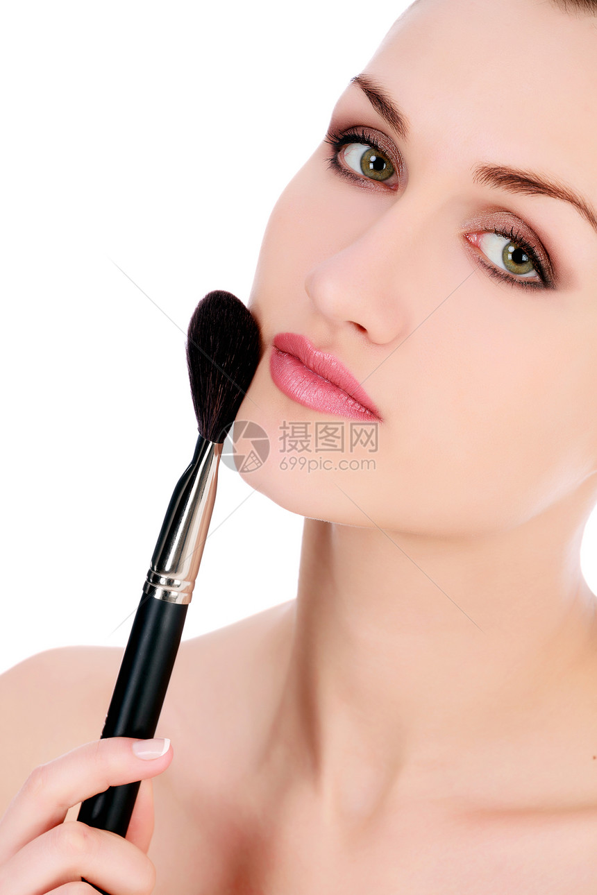 美丽的女人用化妆刷子在脸上化妆图片
