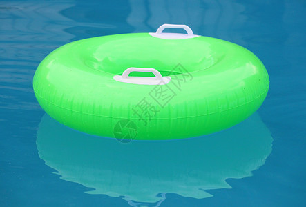 漂浮在蓝色水面上的绿色救生圈图片