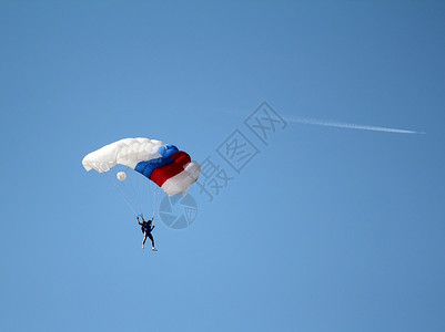 跳伞者和飞机在蓝天图片