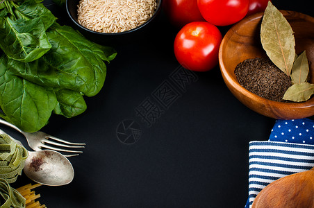 食物背景新鲜蔬菜西红柿辣椒绿色菠菜盐米饭意大利面香料和黑色背景中的厨图片