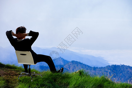 坐在山顶的椅子上仰望天空的年轻商人图片