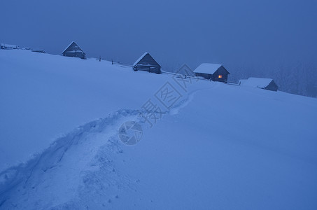 夜间冬季景观与雪中通往山谷小屋的路径山上的童话房子乌克兰图片