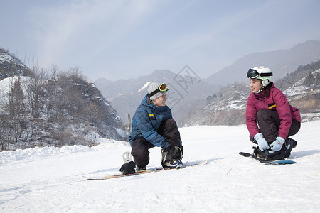 在滑雪场调整滑雪靴的情侣图片