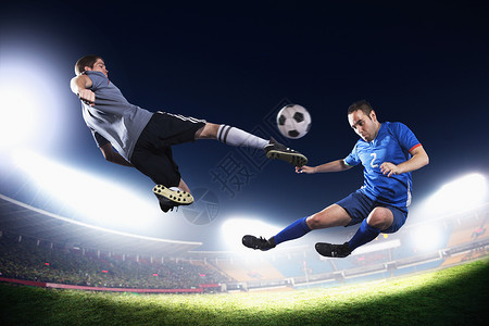 两名中空足球员踢足球晚上在体育场的图片