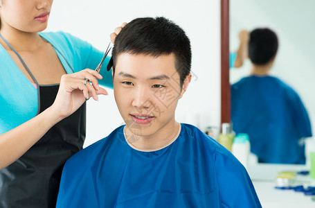 近距离的画面一个年轻男人在前台沙龙剪头发背景图片