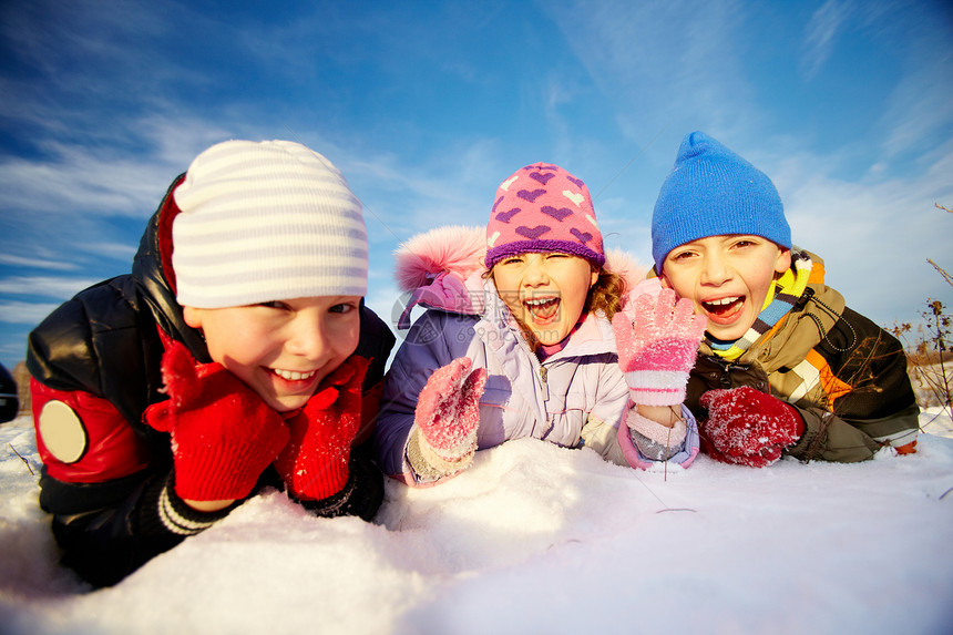 冬天穿冬装的欢乐孩子躺在雪图片