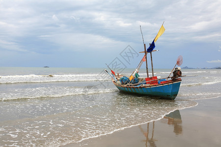 沙滩上搁浅的渔夫船与波浪图片