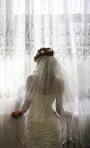 美丽的新娘为婚礼做准备在窗子背背景图片