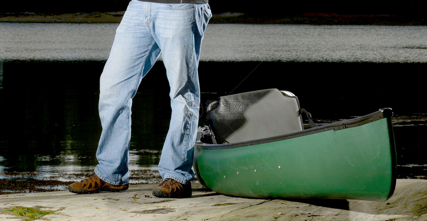 站在河边的人带着绿色的独木舟图片