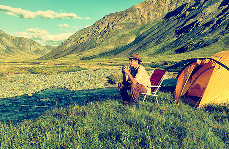 河流附近山区Altai营地游客饮茶的彩色户外图片