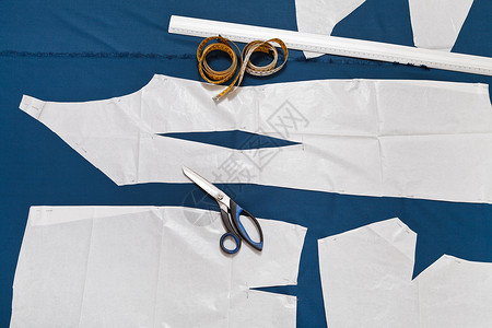 裁缝工具和纸张样本蓝织布上的衣服样图片