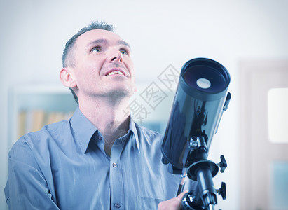 有天文望远镜的人站在窗图片