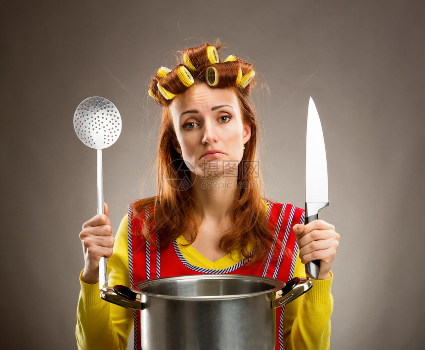 家庭主妇用刀和勺子在厨房做饭图片