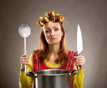 家庭主妇用刀和勺子在厨房做饭图片