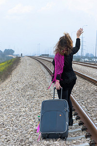 在铁路上的年轻女子在灰色背景图片
