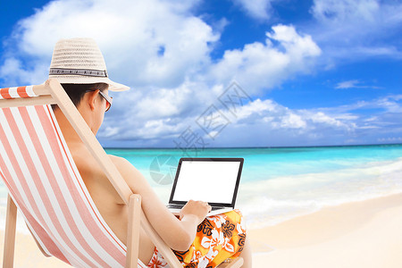 放松的人坐在沙滩椅上使用笔记本电脑图片