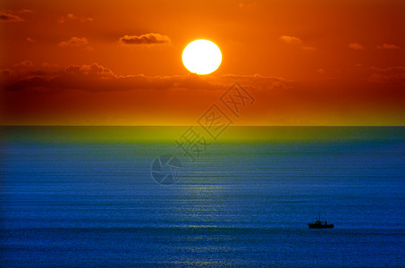 一艘渔船拖网渔船在日落时捕鱼图片