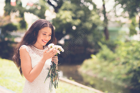 美丽的年轻女士在公园里闻图片