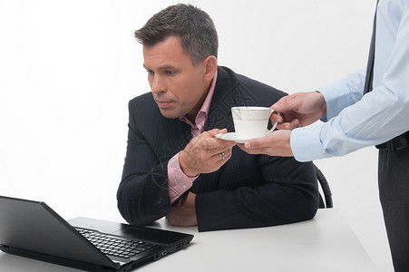 年轻英俊的办公室工人助理为高级经理带来咖啡杯图片
