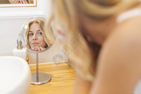女人在小镜子前的面部照护背景图片