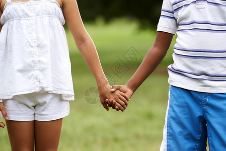爱上白人小女孩和非洲男孩在公园里手牵的异族背景图片