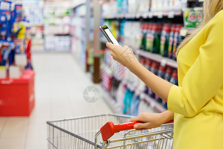 女在超市检查智能手机购物图片