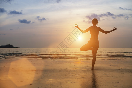 在海滩上冥想的女人的剪影瑜伽图片