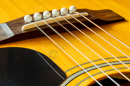 新鲜的吉他琴弦挂在马鞍和桥上背景图片