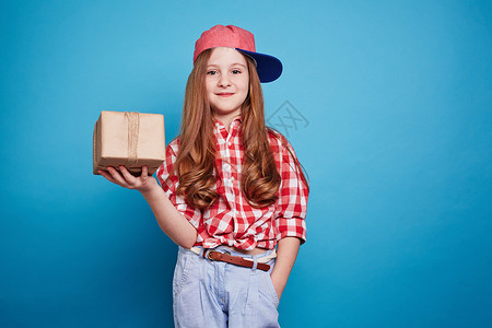 可爱的女孩拿着一个蓝色背景的盒子背景图片