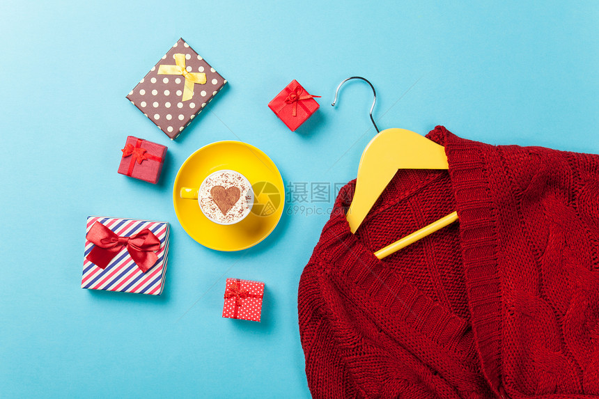 礼物和衣架蓝色背景上的红色毛衣图片