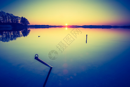美丽的日落在平静的湖面上的老式照片在马祖里湖图片