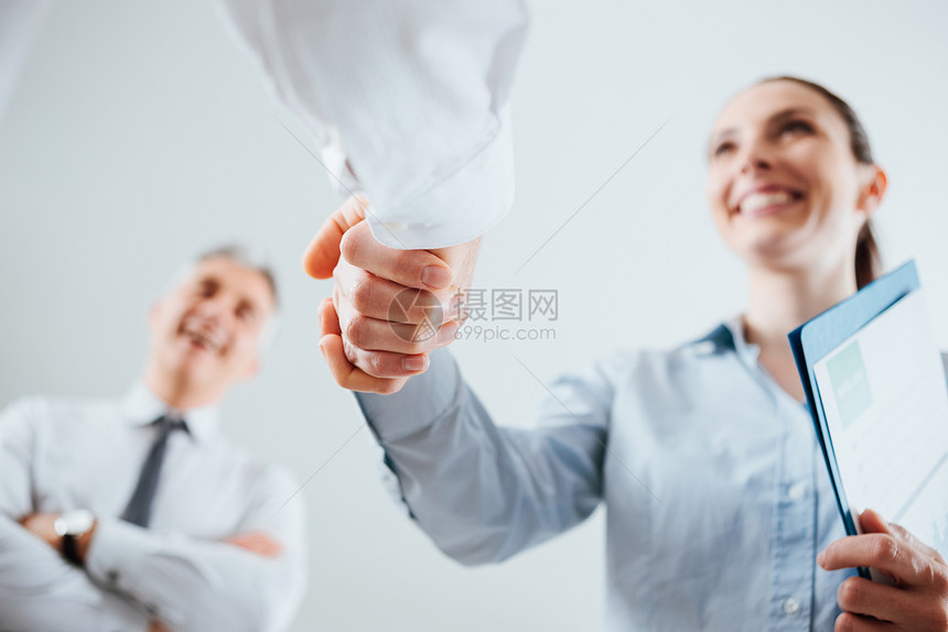自信的商界人士握手和妇女微笑和协议概念图片