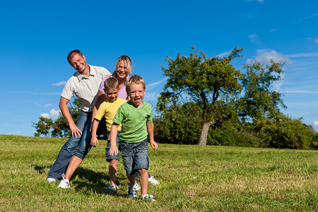 和两个小男孩在草地上玩耍的快乐家庭图片