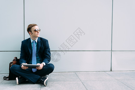 身戴太阳眼镜的商人坐在地上手里图片