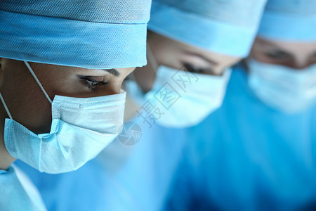 三名外科医生在手术室工作复苏医学团队戴着防护口罩拯救病人手术和图片