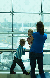 母亲和孩子的母亲在机场等候时看着飞机图片