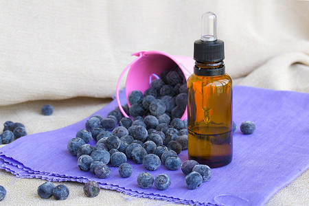 香水瓶蓝莓种子基本油和紫花布背景图片