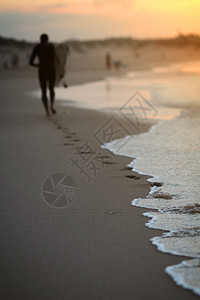 日落时在海滩上奔跑的冲浪者的特写图像沙滩上的脚印冲浪者在沙滩上的脚印图片