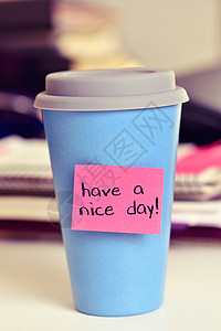 纸条上的粉色粘贴纸条与办公室桌上的蓝杯咖啡或茶连在一图片