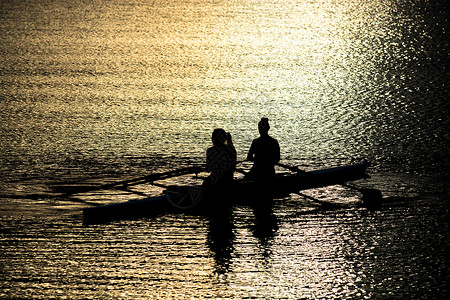 日落湖双桨中的女赛艇运动员背景图片