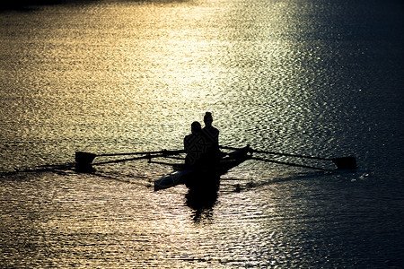 日落湖双桨中的女赛艇运动员背景图片