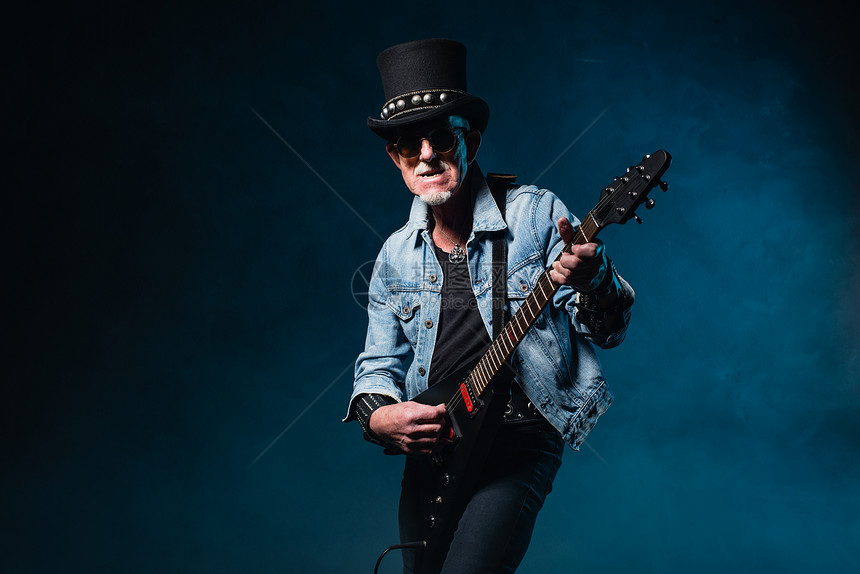 在深蓝色背景面前拿着电动飞吉他的高图片