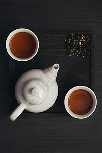 深色木盘上的茶杯和茶壶背景图片