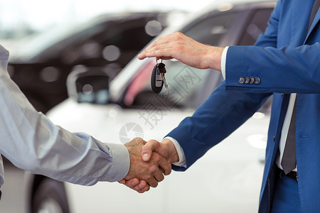 两名商人在汽车秀上卖车时握背景图片