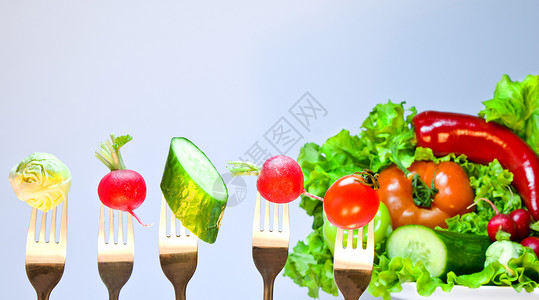 在新鲜蔬菜和生菜的构成背景上与蔬菜结合的叉图片