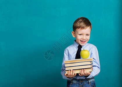 孩子拿着书的小学生反对黑板的快乐微笑的小孩看着相机学校理图片