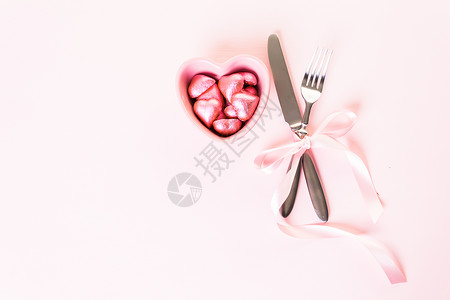 粉红色背景上带有粉红色丝带的餐具图片