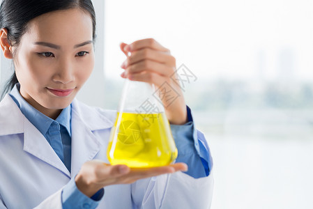 越南年轻科学家在实验室里用黄色液体研究瓶子的越图片