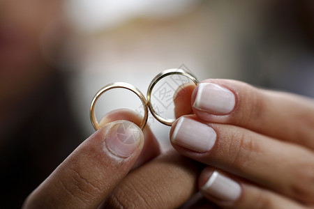 两只手拿着两个金戒指结婚背景图片